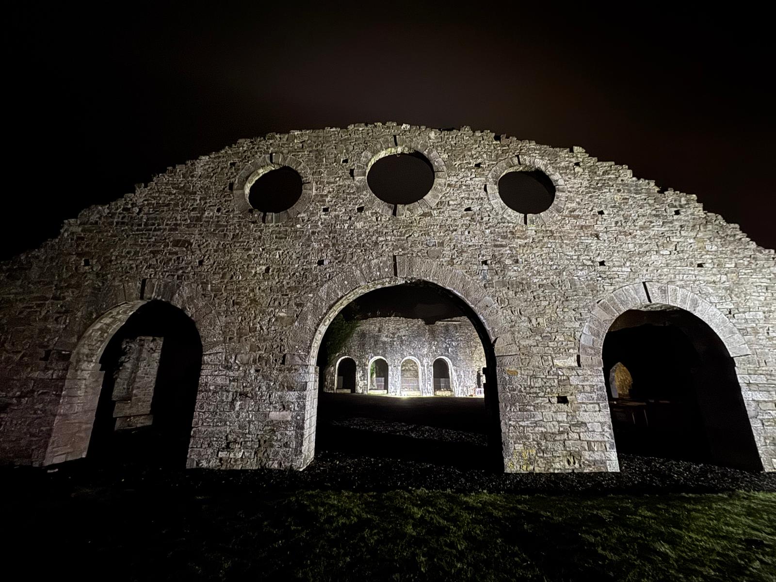 The historic Iron Works ruins lit at night inside Heritage Park